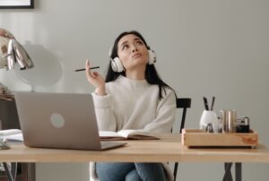 Mujer con audífonos pensando en su oficina y frente a la computadora